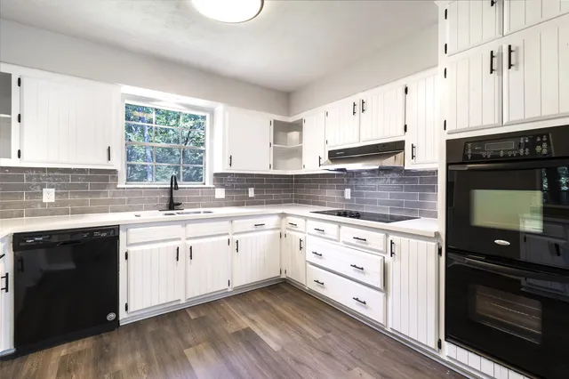 a kitchen with granite countertop white cabinets stainless steel appliances and a window