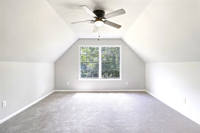 an empty room with a chandelier fan and windows