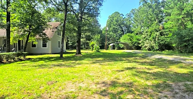 a view of a house with a big yard and large trees