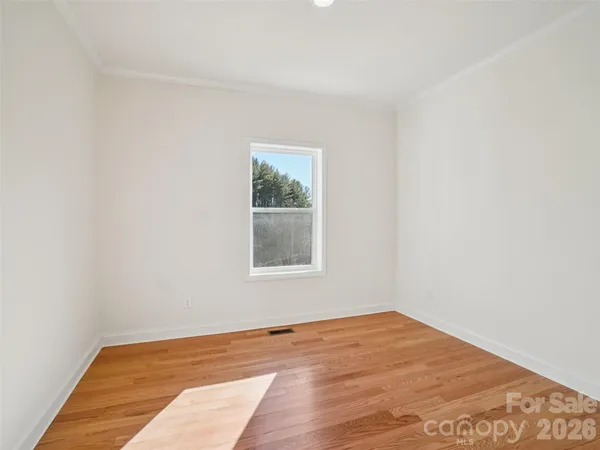 an empty room with wooden floor and a window