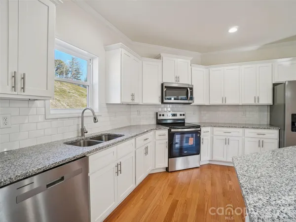 a kitchen with granite countertop a sink stainless steel appliances and cabinets