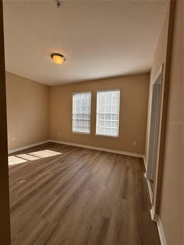 an empty room with wooden floor and windows