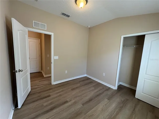 an empty room with wooden floor and entrance