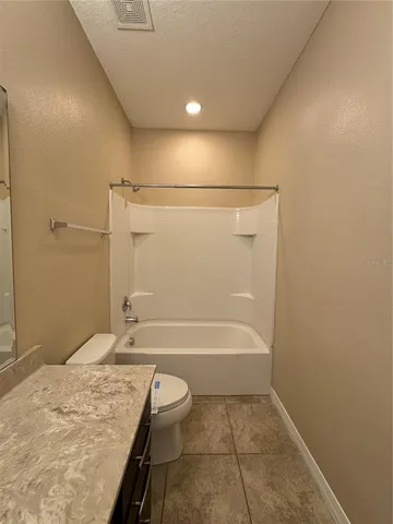 a bathroom with a granite countertop sink a toilet and bathtub