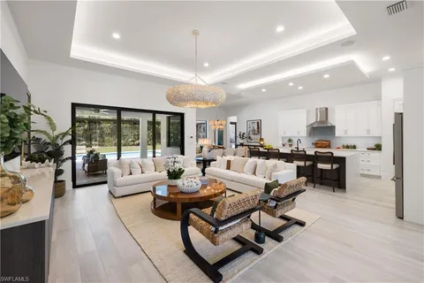a living room with furniture kitchen view and large windows