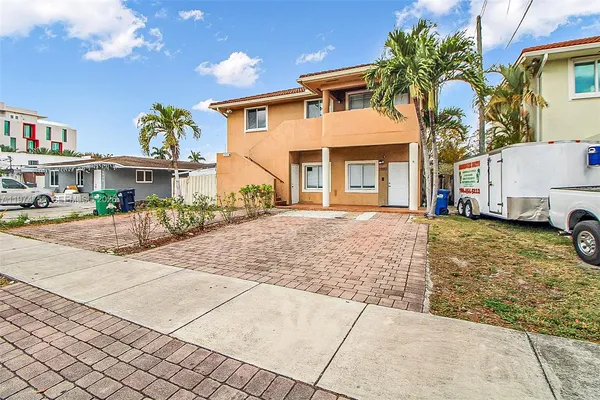 a front view of a building with lots of cars parked on the road