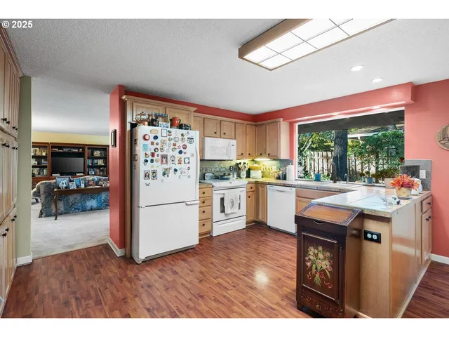 a kitchen with stainless steel appliances granite countertop a refrigerator a sink dishwasher a stove with white cabinets and wooden floor