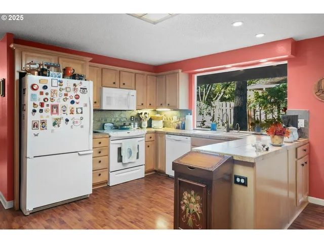 a kitchen with stainless steel appliances granite countertop a refrigerator a sink dishwasher and white cabinets with wooden floor