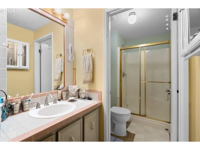 a bathroom with a double vanity sink toilet mirror and shower