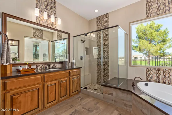 a spacious bathroom with a double vanity sink a large mirror and a bathtub