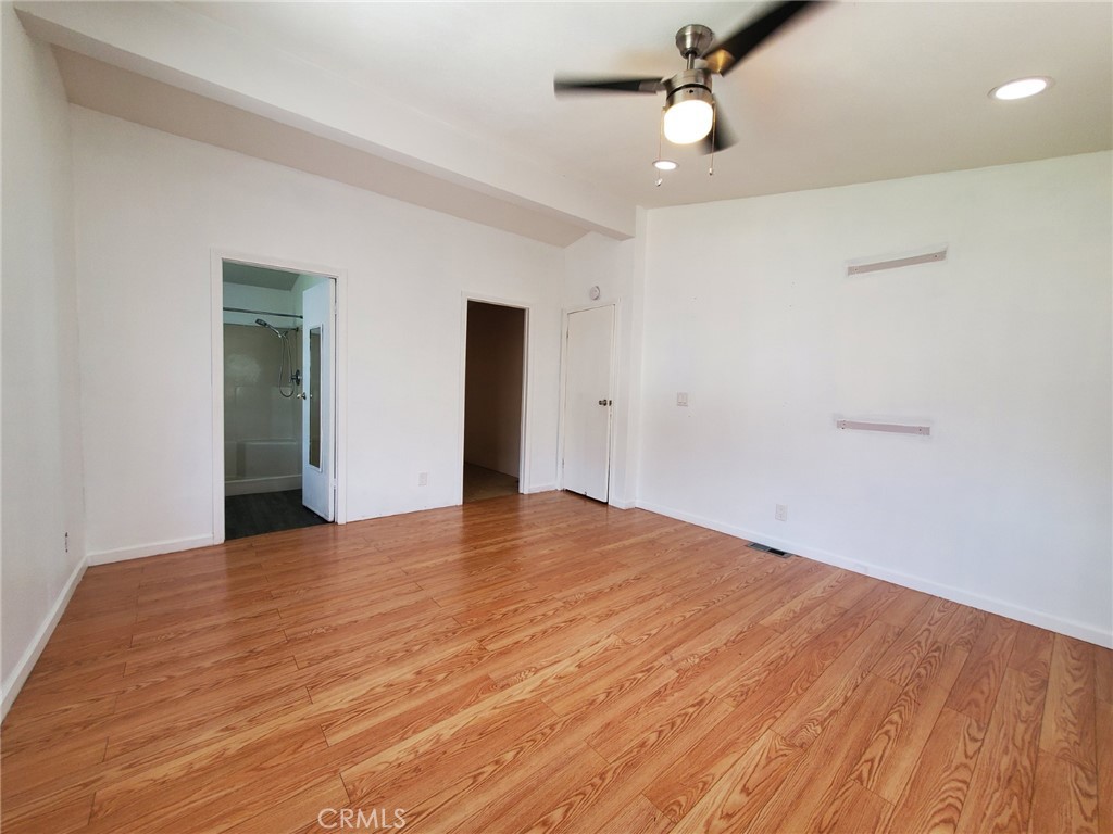 27361 Sierra Highway, Unit 19 Canyon Country, CA 91351 - Photo 20 of 26 an empty room with wooden floor ceiling fan and window