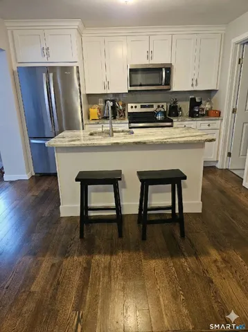 a kitchen with stainless steel appliances a dining table chairs microwave and refrigerator