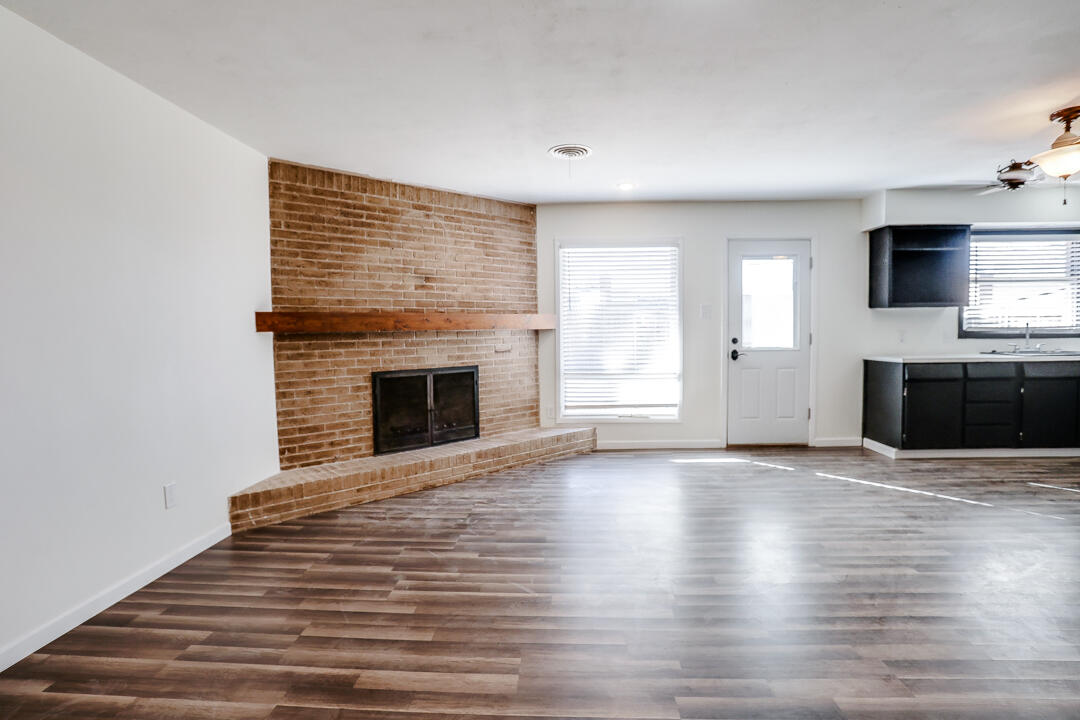 2123 66th Street Lubbock, TX 79412 - Photo 4 of 16 a view of empty room with wooden floor and fireplace