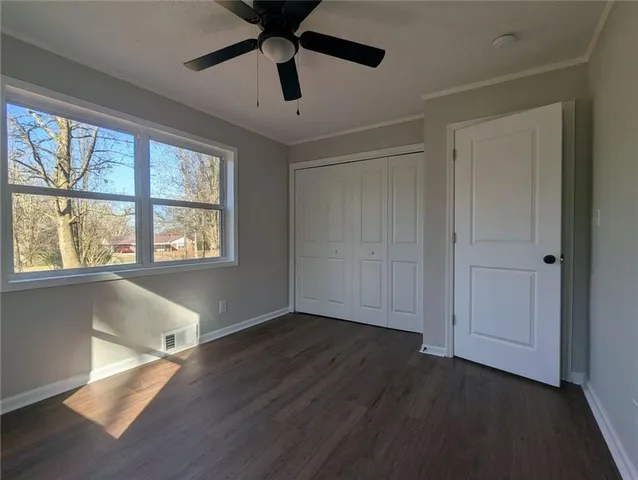 an empty room with wooden floor fan and windows