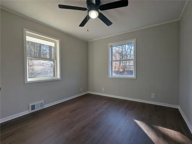 a view of an empty room with wooden floor and window