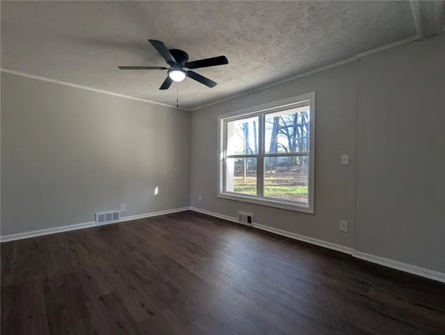 an empty room with wooden floor fan and windows