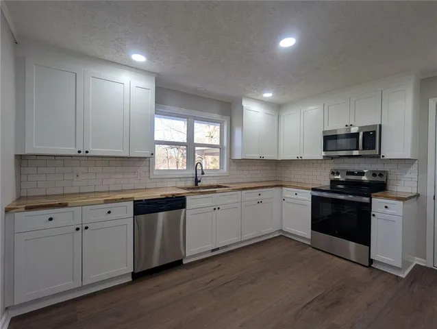 a kitchen with granite countertop white cabinets and appliances