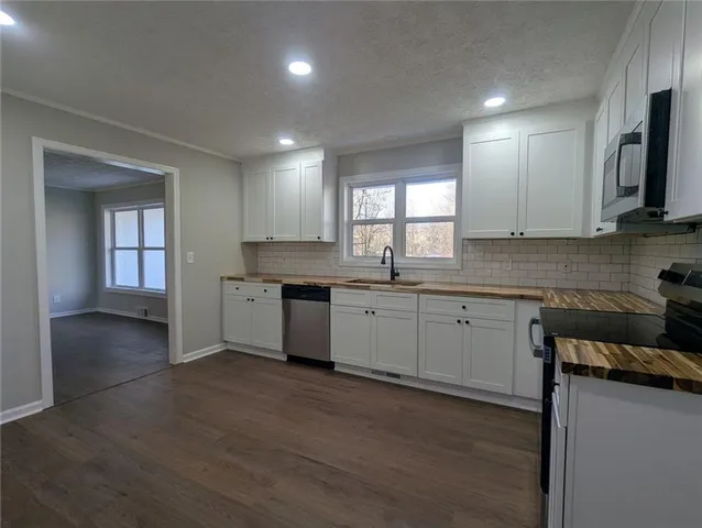 a kitchen with a sink wooden floor and black stainless steel appliances