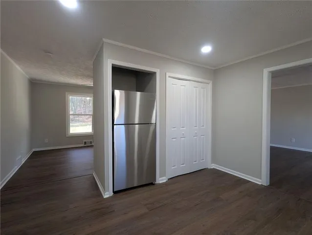 a view of empty room with wooden floor and kitchen