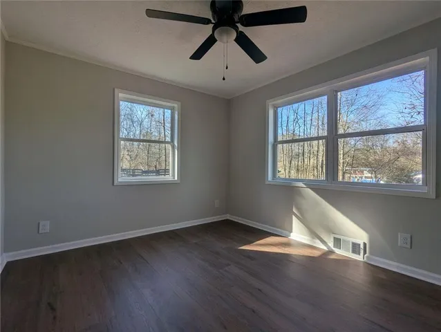 a view of empty room with wooden floor and fan