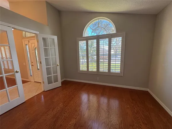 a view of an empty room with wooden floor and a window