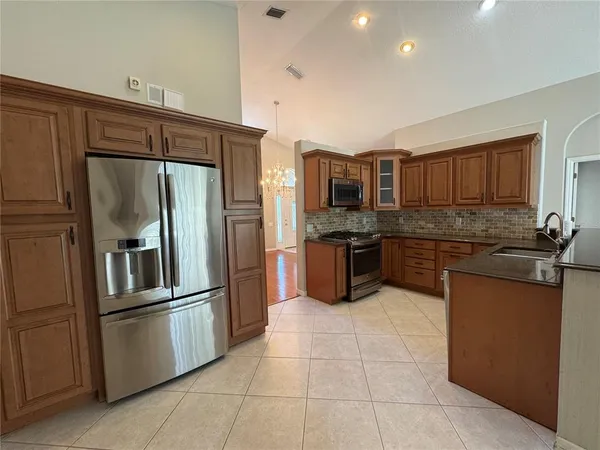 a kitchen with granite countertop a refrigerator and a stove top oven