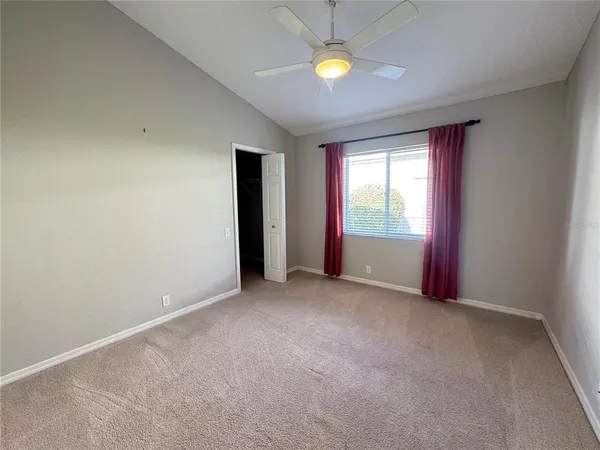 an empty room with windows and ceiling fan