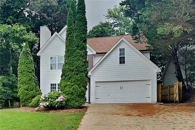 a front view of house with yard and trees all around
