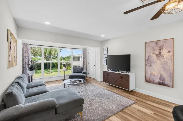 a view of a dining room and livingroom with furniture wooden floor a rug a painting and a chandelier