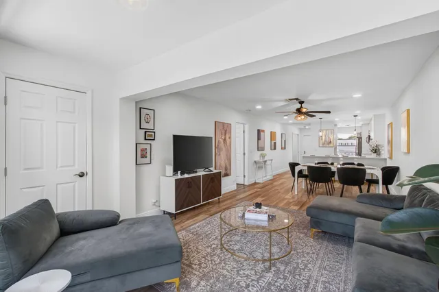 a kitchen with stainless steel appliances a refrigerator a stove a sink a dining table and chairs with wooden floor