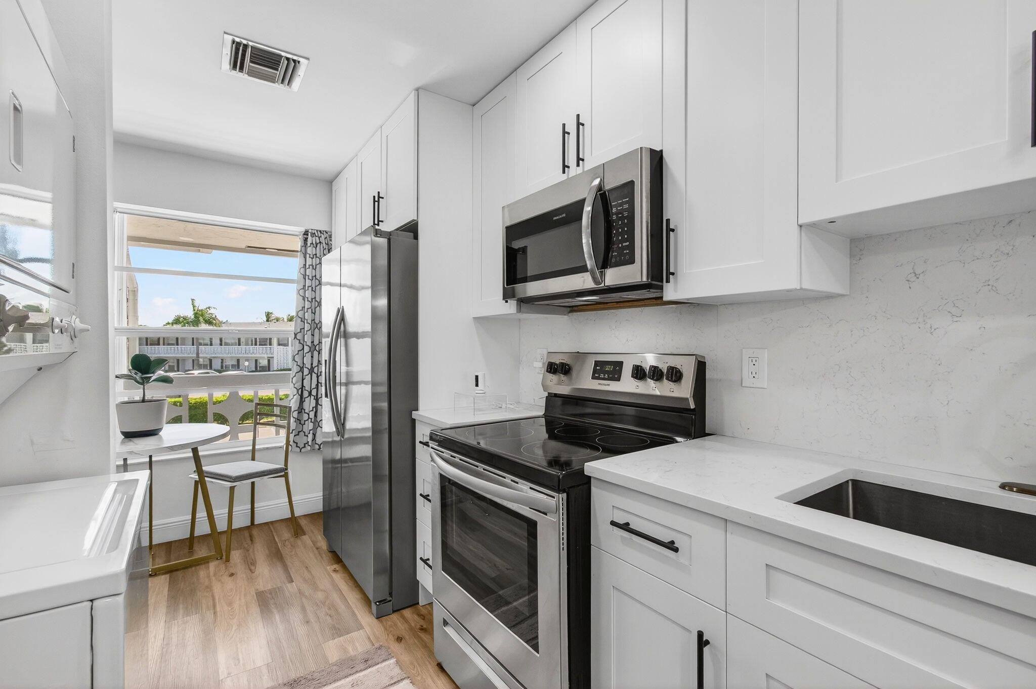 2825 Southwest 13th Street, Unit 204 Delray Beach, FL 33445 - Photo 21 of 62 a kitchen with stainless steel appliances white cabinets and a stove top oven