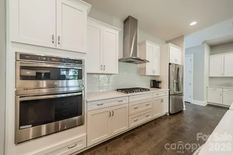 a kitchen with stainless steel appliances white cabinets and wooden floors