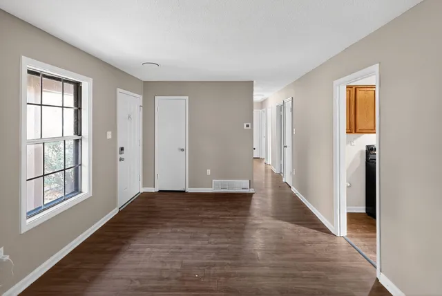 a view of an empty room with window and wooden floor