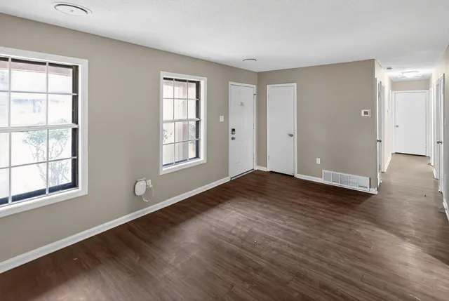 an empty room with wooden floor and windows