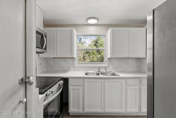 a kitchen with white cabinets and stainless steel appliances
