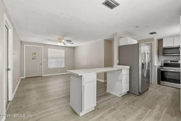 an empty room with wooden floor chandelier fan and windows