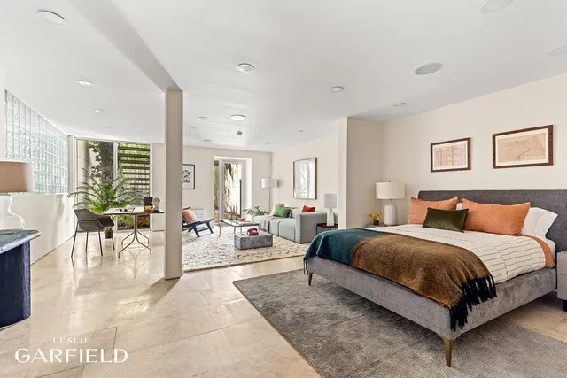 a spacious bedroom with a bed a table and with potted plants