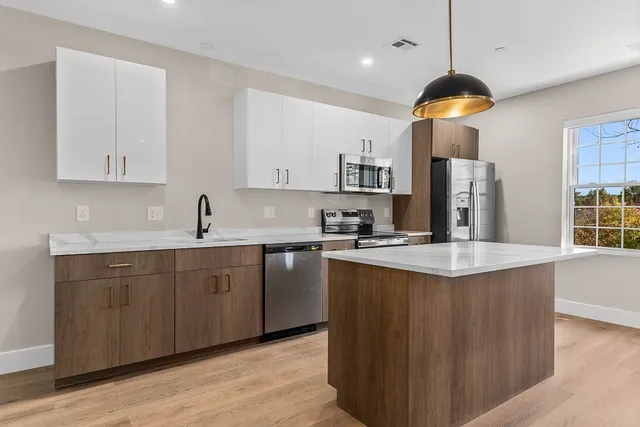 a kitchen with stainless steel appliances granite countertop a sink a stove a refrigerator a microwave oven with white cabinets and wooden floor