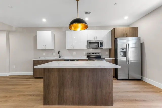a view of a kitchen with wooden floor and an empty room