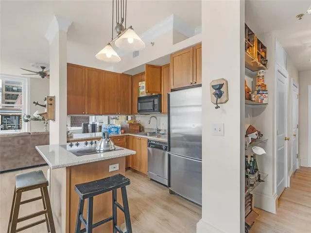 a kitchen with stainless steel appliances granite countertop a refrigerator a sink dishwasher a dining table and chairs with wooden floor