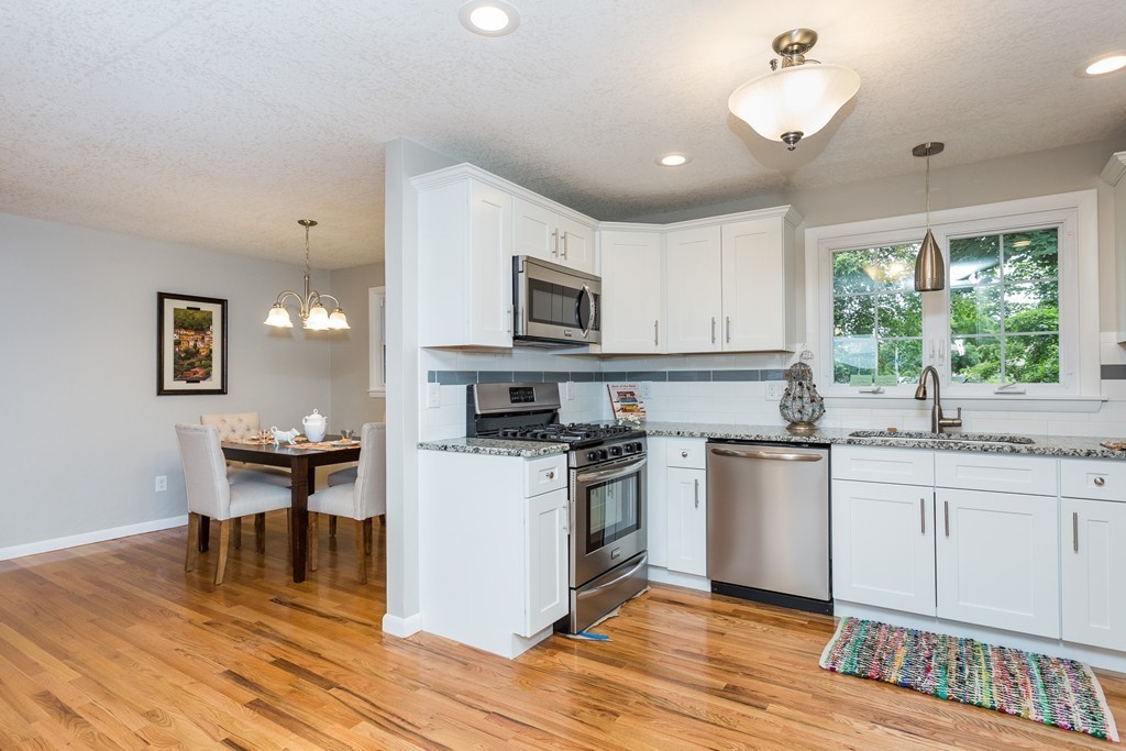 29 Mary Coburn Road Springfield, MA 01129 - Photo 3 of 30 a kitchen with granite countertop a stove top oven a sink dishwasher a dining table and chairs with wooden floor