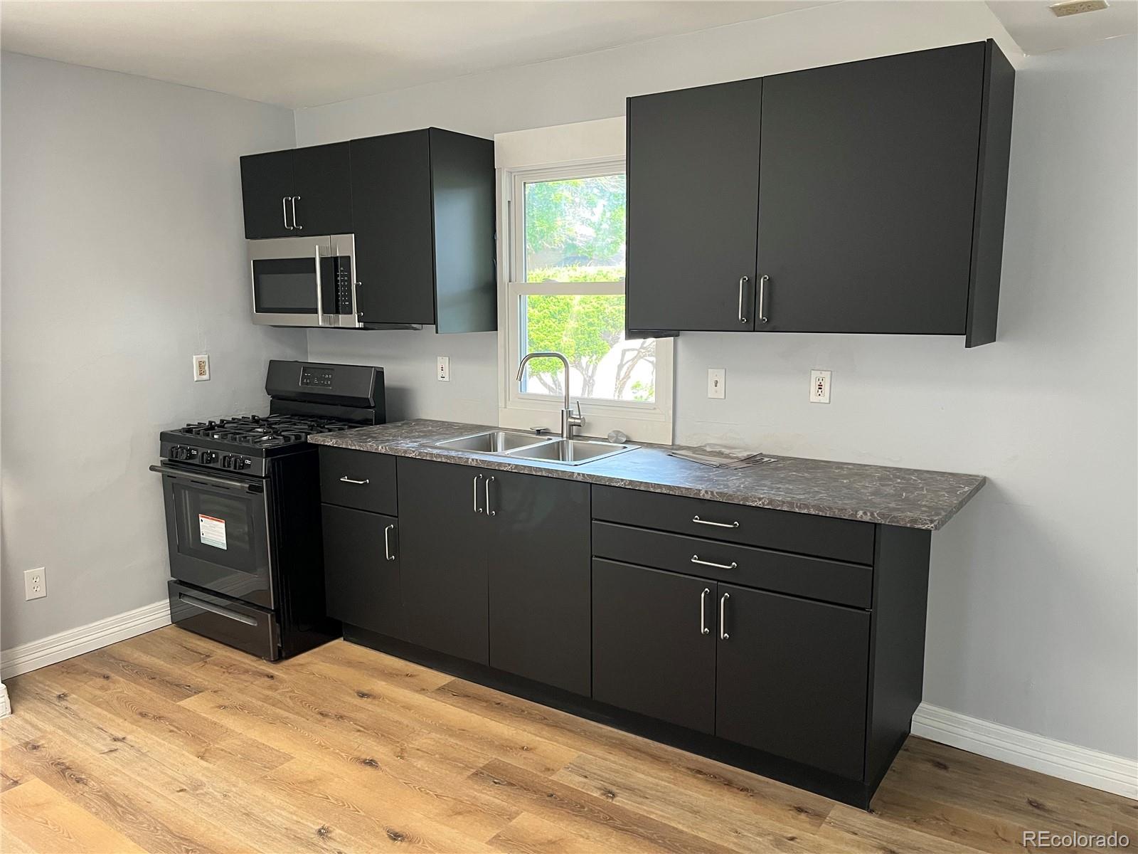 4315 Balsam Street, Unit A Wheat Ridge, CO 80033 - Photo 6 of 21 a kitchen with stainless steel appliances granite countertop a sink stove and microwave
