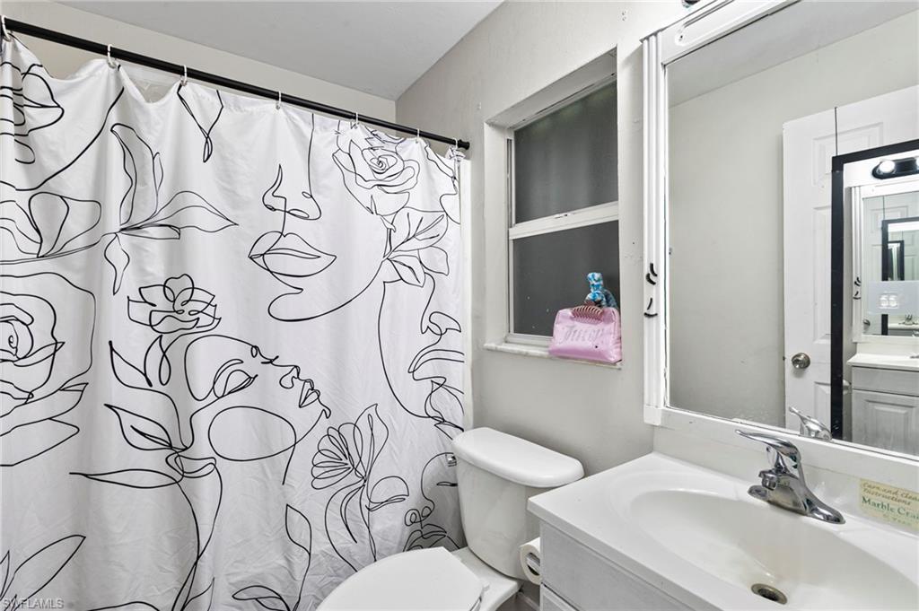 8264-8268 Matanzas Road Fort Myers, FL 33967 - Photo 24 of 33 a bathroom with a white shower curtain next to a white sink and a mirror