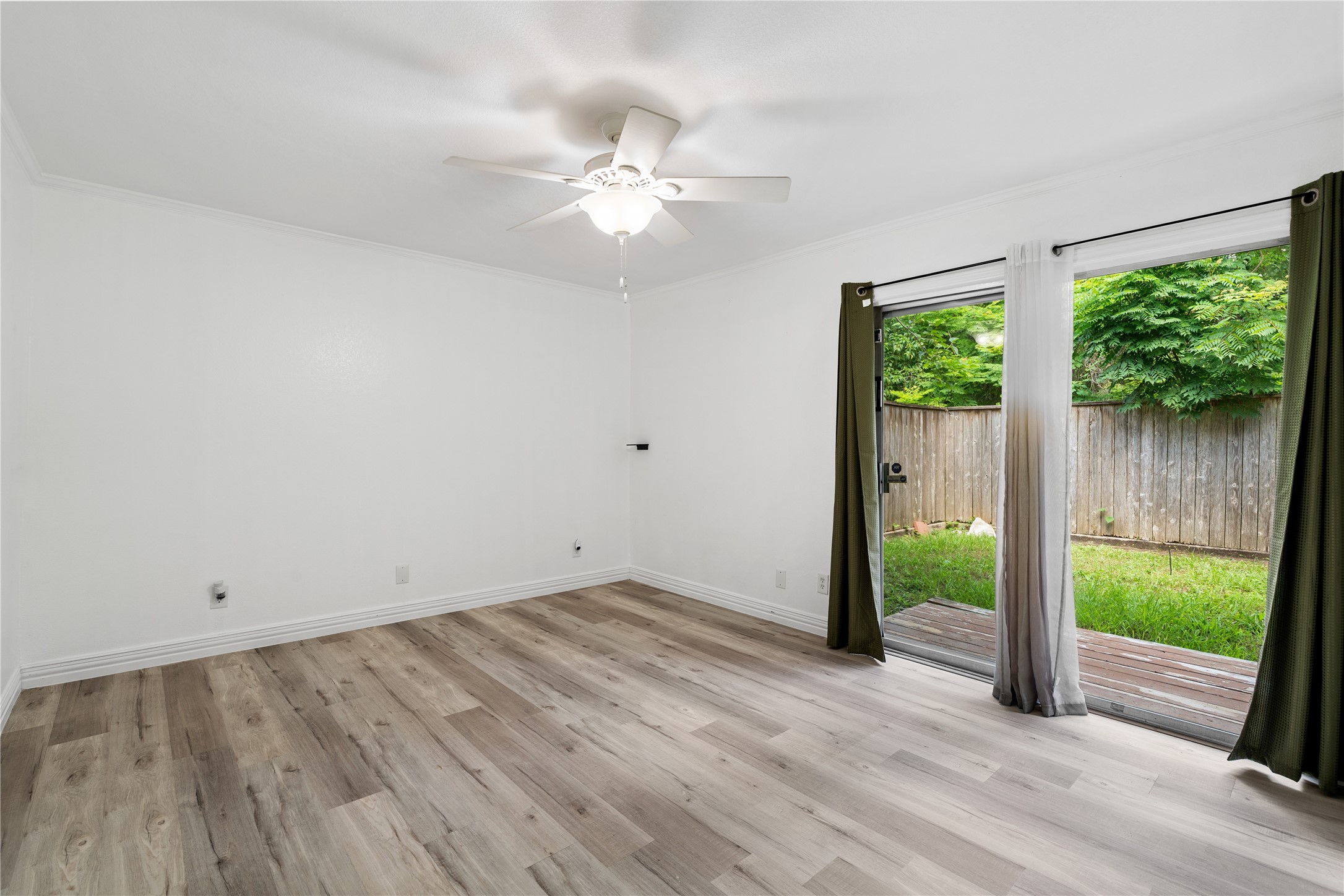 6303 Crab Orchard Road, Unit 3 Houston, TX 77057 - Photo 23 of 30 This secondary bedroom is a bright, airy escape. Huge sliding glass doors offer direct access to the private backyard, flooding the room with views of the lush greenery. Like the rest of the home, it features a chic white ceiling fan and impeccable modern flooring.
