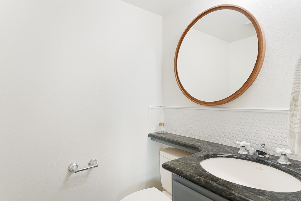 4966 Park Drive Carlsbad, CA 92008 - Photo 20 of 45 a bathroom with a granite countertop sink a mirror and a toilet