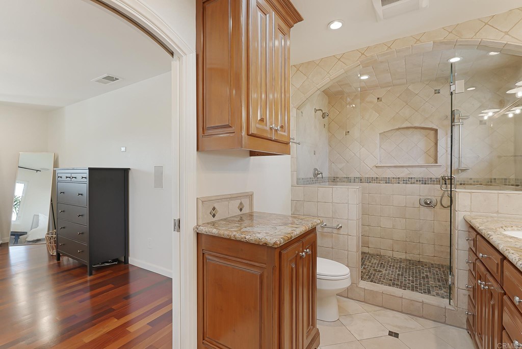 4966 Park Drive Carlsbad, CA 92008 - Photo 32 of 45 a bathroom with a granite countertop sink a toilet a mirror and shower