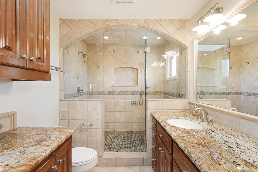 4966 Park Drive Carlsbad, CA 92008 - Photo 34 of 45 a bathroom with a granite countertop sink a toilet a large mirror and shower