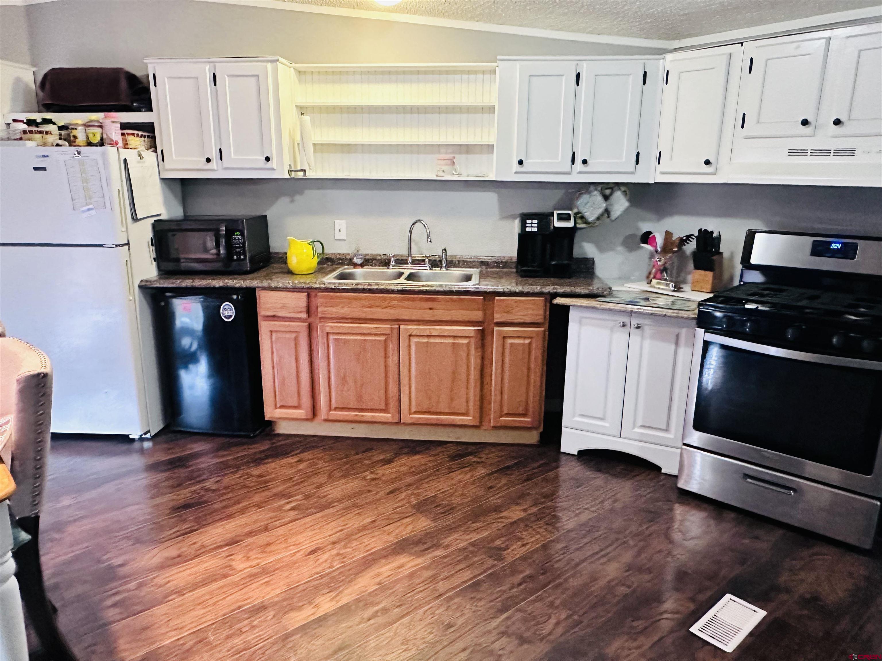 62880 Lasalle Road, Unit 174 Montrose, CO 81401 - Photo 12 of 23 a kitchen with granite countertop wooden floors stainless steel appliances and cabinets