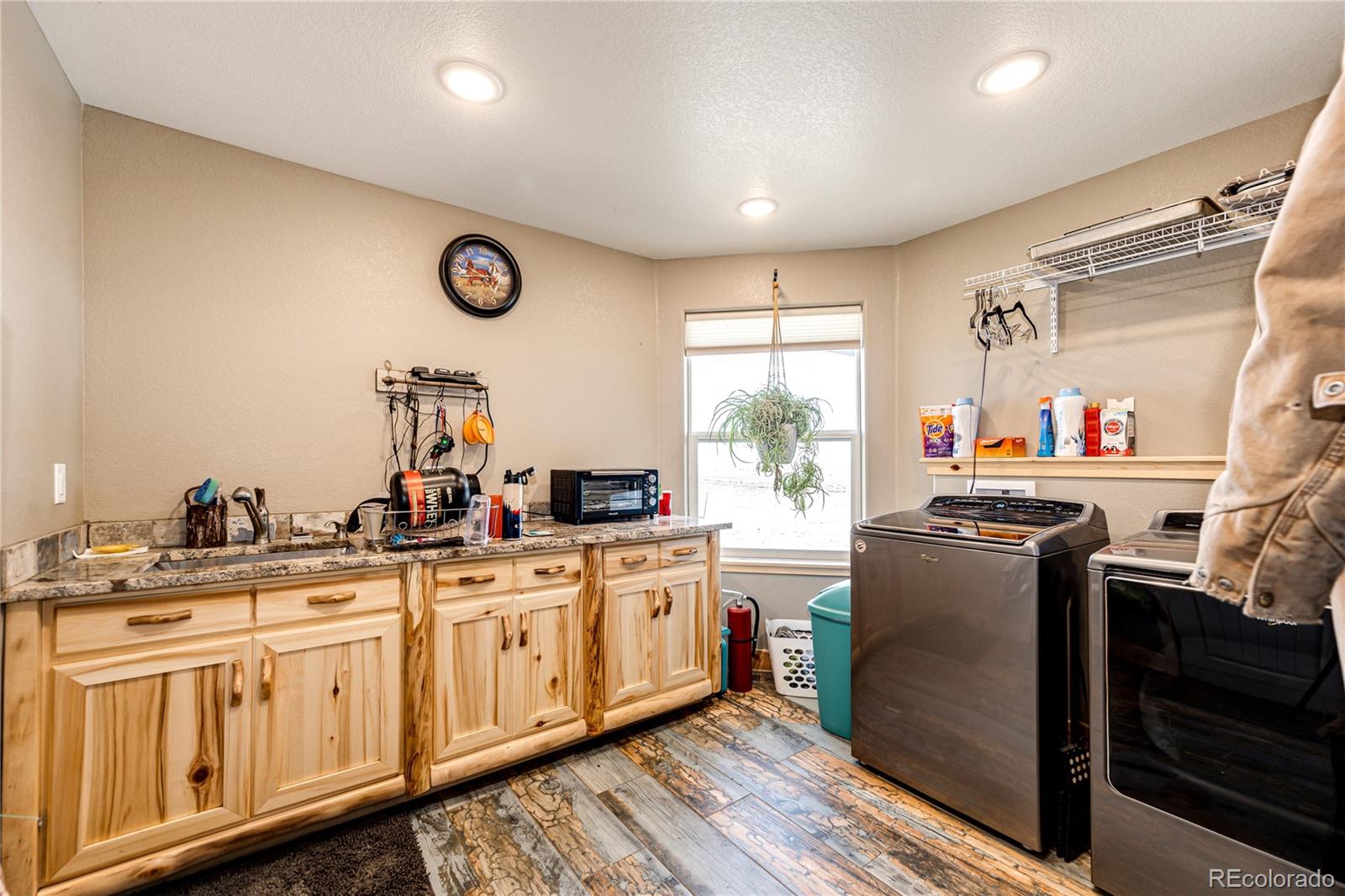 3955 South Behrens Road Byers, CO 80103 - Photo 12 of 32 a kitchen with stainless steel appliances granite countertop a stove a sink dishwasher and white cabinets with wooden floor