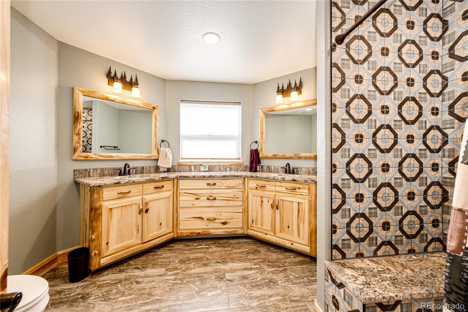 3955 South Behrens Road Byers, CO 80103 - Photo 22 of 32 a spacious bathroom with a granite countertop sink and a mirror